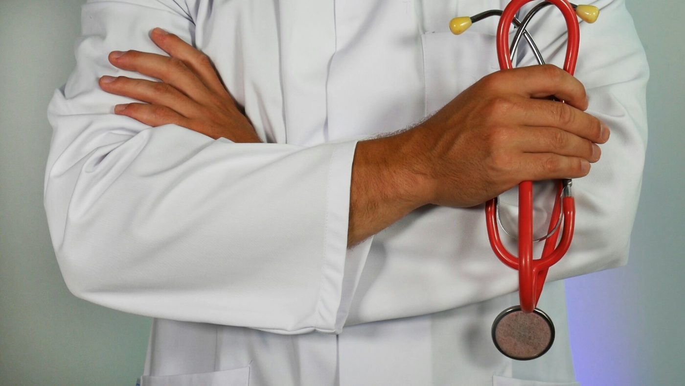 Doctor in a white coat holding a stethoscope, ready to review a care programme